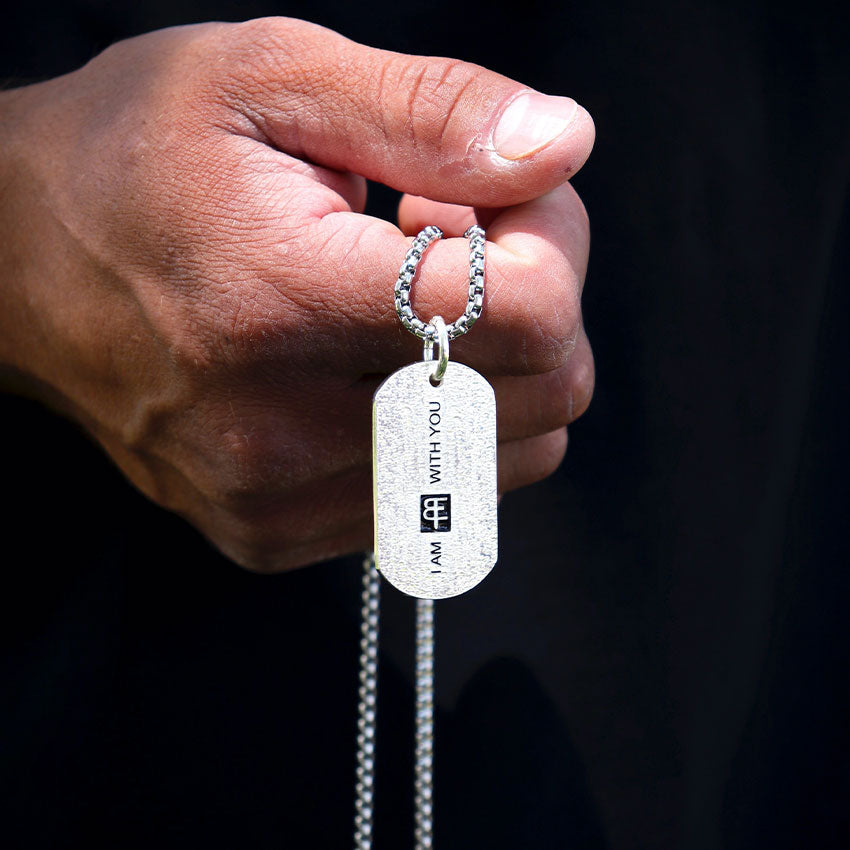 man holding a dog tag with I am with you engraved